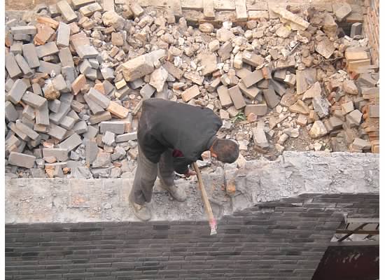 This man was in a nice suit smashing a rock wall.  